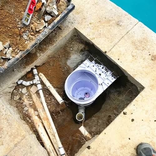 Skimmer neuf en cours de raccordement sous la plage de la piscine